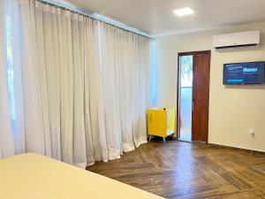 a room with white curtains and a sliding door at Pousada Iandê Patacho in Pôrto de Pedras