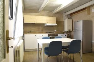 uma cozinha com uma mesa branca e cadeiras azuis em La Piccola Casa di Via Ricotti em Castelguglielmo