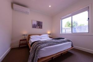 una camera da letto con un grande letto e una finestra di Campbells Cottage by Ready Set Host a Frankston