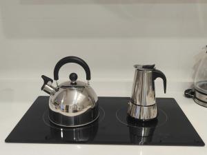 a tea kettle and coffee pot on a black tray at M&D Centro Málaga in Málaga
