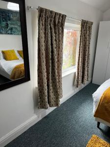 a bedroom with a bed and a mirror and a window at Cheerful 3 bedroom entire home - newly furnished in Stockport