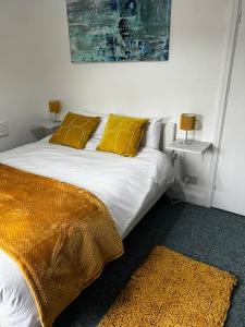 a bedroom with a bed with yellow pillows and a rug at Cheerful 3 bedroom entire home - newly furnished in Stockport