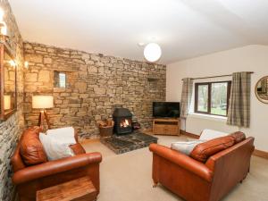 a living room with leather furniture and a stone wall at Bullfinch Cottage in Leominster
