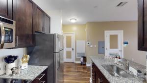 eine Küche mit einem Kühlschrank aus Edelstahl und Holzschränken in der Unterkunft Corporate King Malden Square # 431 in Malden