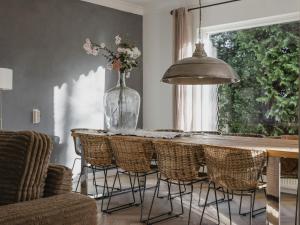 uma mesa de jantar com cadeiras e um vaso com flores em Stylish holiday home in Leende with garden em Leende