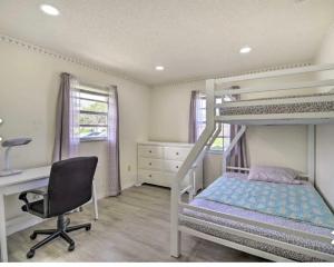 ein Schlafzimmer mit einem Etagenbett, einem Schreibtisch und einem Stuhl in der Unterkunft Vacation Home 4 Bedrooms 3Baths 10 beds home in Melbourne