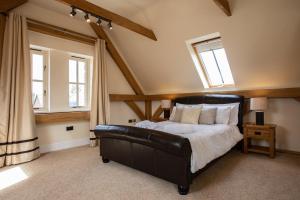 a bedroom with a black leather bed and two windows at The Old Barn, Newclose Farm in Yarmouth