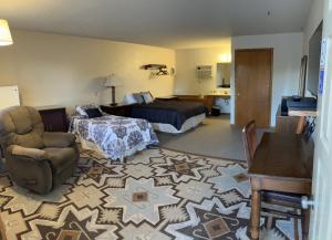 Beaver CityにあるFurnas County Lodgingのベッドと椅子付きのホテルルーム