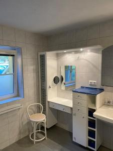 La salle de bains est pourvue d'un lavabo, d'un miroir et d'une chaise. dans l'établissement Ferienwohnung Bernhardiner, à Nauders