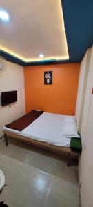 a bed in a room with an orange wall at Swapnpurti yatri niwas in Kolhapur