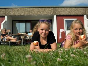 dwie małe dziewczynki leżące na trawie trzymające jabłka w obiekcie 6 person holiday home in Allinge w mieście Allinge