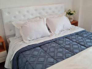 1 cama con almohadas blancas y edredón azul en Precioso departamento en zona gastronomica con cochera en Lanús