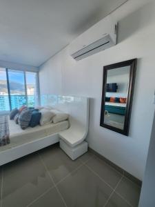 una camera bianca con letto e specchio di Apartaestudio Reserva del Mar Playa Salguero Santa Marta a Santa Marta