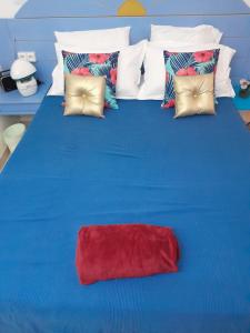 a blue bed with a red pillow on it at My Tiny Caritan- Petit coin de paradis- Bungalow de vacances- jardin, plage, piscine attenante in Sainte-Anne