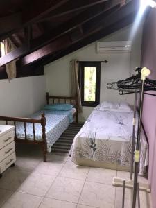 1 dormitorio con 2 camas y ventana en Casa Centro de Bombinhas, en Bombinhas