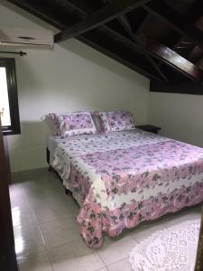 1 dormitorio con 1 cama con colcha rosa en Casa Centro de Bombinhas, en Bombinhas