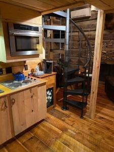 a kitchen with a spiral staircase in a tiny house at 1850’s Settlers Cabin at Wethero Ridge & Theater in Hendersonville