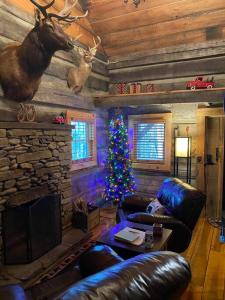 a living room with a christmas tree and a fireplace at 1850’s Settlers Cabin at Wethero Ridge & Theater in Hendersonville