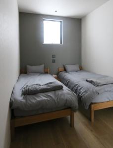 two twin beds in a room with a window at Niseko Bisha 美舎 Onsen Villas in Niseko