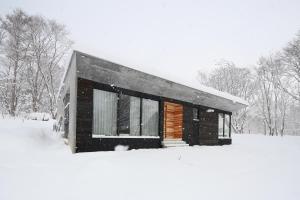 una casa cubierta de nieve en un patio en Niseko Bisha 美舎 Onsen Villas en Niseko