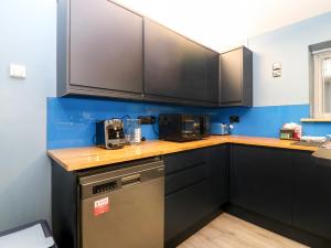 a kitchen with black appliances and blue walls at The Cavern at the Tavern in Blairgowrie