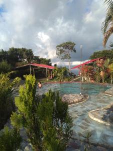 uma piscina num resort com uma pessoa na água em PosadaManduka Eco-Hostel em Villavicencio