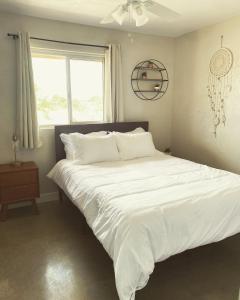 a bedroom with a large white bed with a window at Casa Del Desierto - Panoramic Views - Pet Friendly - Fire Pit in Joshua Tree