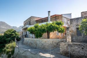 Una casa vieja con un árbol delante. en Traditional cottage near Kissamos and Falassarna 2 feel like home properties, en Áyios Vasílios