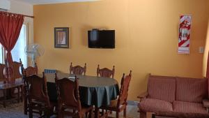 a dining room with a table and chairs and a tv on the wall at Cabañas Los Pinos in Potrero de los Funes