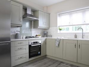 a kitchen with white cabinets and a stove top oven at Yew Cottage in Belford