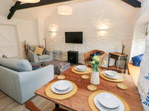 una sala de estar con una mesa de madera con platos. en Bluebell Cottage en Tenby
