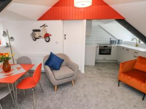 a living room with a table and chairs and a kitchen at Clementine Cottage in Tenby