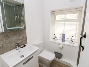 ein Badezimmer mit Toilette und Waschbecken und einem Fenster in der Unterkunft Bluebell Cottage in Tenby + 20 Fotos