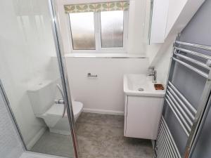 a bathroom with a toilet and a sink and a window at Clementine Cottage in Tenby +16 photos