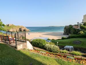 a view of a beach with a bench and the ocean at Bluebell Cottage in Tenby