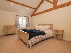 a bedroom with a bed and a dresser and a window at Meadowside Barn in Preston