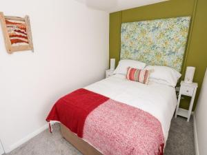 a bedroom with a bed with a red and white blanket at Rosemary Cottage in Tenby