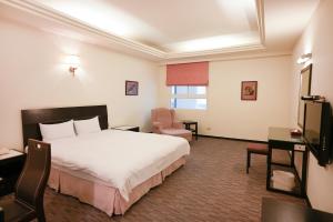 Habitación de hotel con cama y silla en Herkang Hotel en Taichung