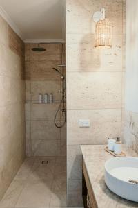 a bathroom with a shower and a white sink at Sunsets on Martyrs Luxury Coastal Beach House Peterborough in Peterborough