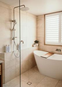 a bathroom with a bath tub and a shower at Sunsets on Martyrs Luxury Coastal Beach House Peterborough in Peterborough