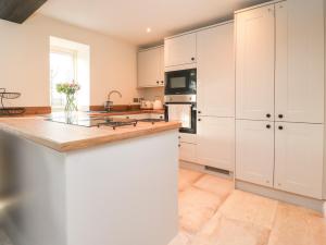 a kitchen with white cabinets and a counter top at The Byre in Preston