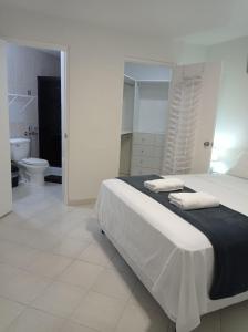 een witte slaapkamer met een bed en een toilet bij Doña Nancy in Panama-Stad