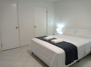 een witte slaapkamer met een bed met twee handdoeken erop bij Doña Nancy in Panama-Stad