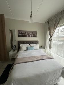 1 dormitorio con 1 cama blanca grande y ventana en The Blyde Riverwalk Estate, Crystal Lagoon, Pretoria east en Pretoria