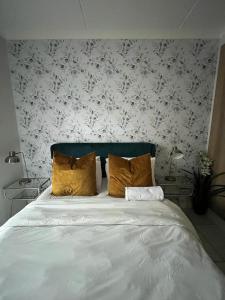 1 cama con 2 almohadas en un dormitorio con papel pintado con motivos florales en The Blyde Riverwalk Estate, Crystal Lagoon, Pretoria east en Pretoria
