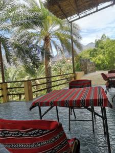 un patio con 3 sillas, una mesa y una palmera en Balad Sayt Heritage Inn en Bilād Sayt
