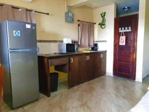 a kitchen with a refrigerator and a table with a microwave at Beach Side Condos Caye Caulker by CCVH in Caye Caulker