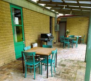 eine Außenterrasse mit Tischen, Stühlen und einem Grill in der Unterkunft Hunter Valley Travellers Rest Motel in Cessnock