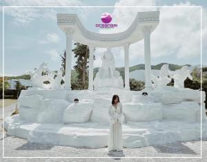 una mujer con un vestido blanco parada frente a una escultura de hielo en Oceanami villa Resort từ 1PN đến 5PN - Đầy đủ tiện nghi - Bếp nấu - BBQ - Hồ bơi - Sát Biển Long Hải - Hồ Tràm - Vũng Tàu en Long Hai