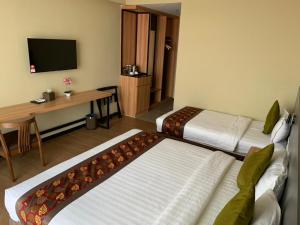 um quarto de hotel com duas camas e uma secretária e uma televisão em Wing Tat Grand Hotel em Semporna